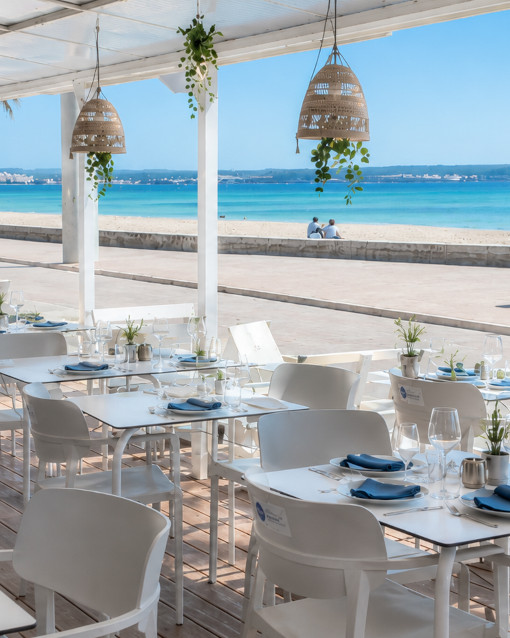Terraza de H2O Beach Club al atardecer con mesas, sillones y vistas al mar