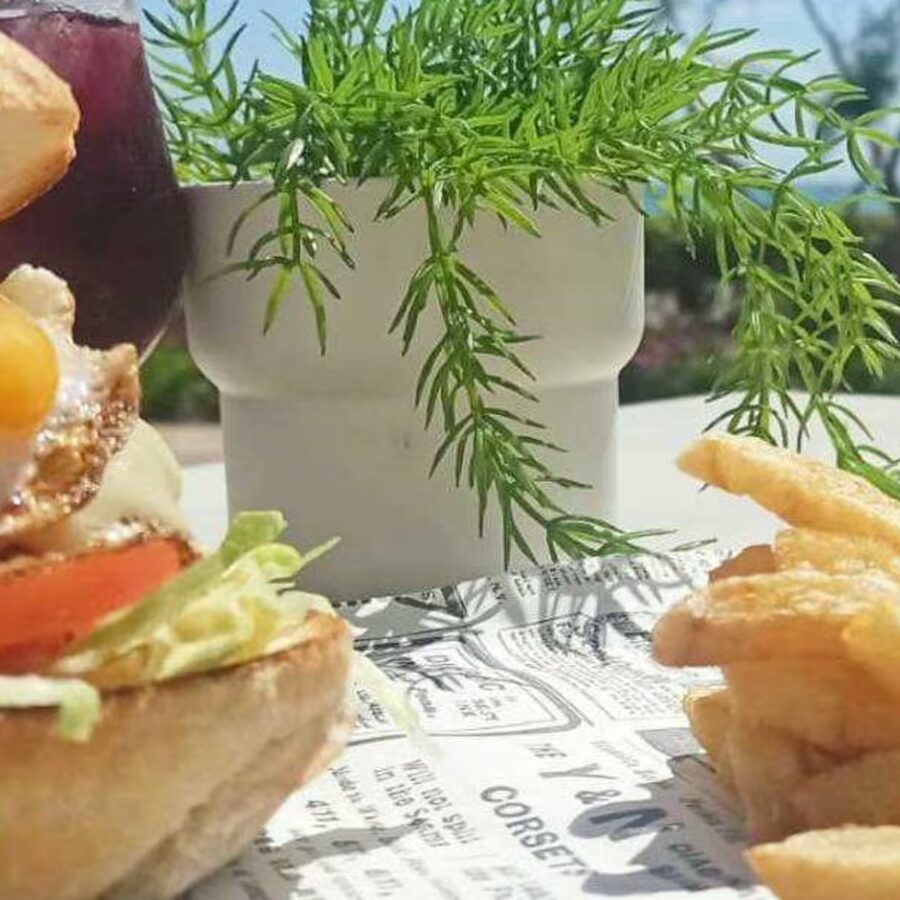 Hamburguesa con patatas y refresco en mesa de terraza