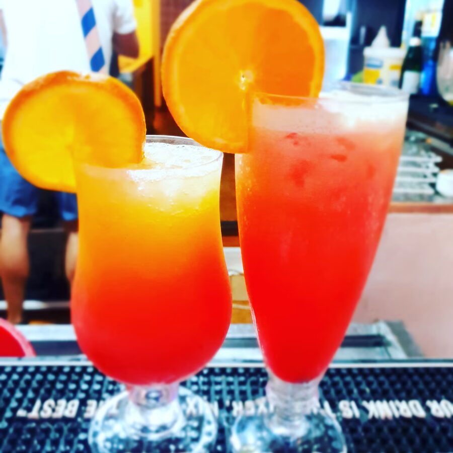 Dos cócteles afrutados con rodajas de naranja en copa larga