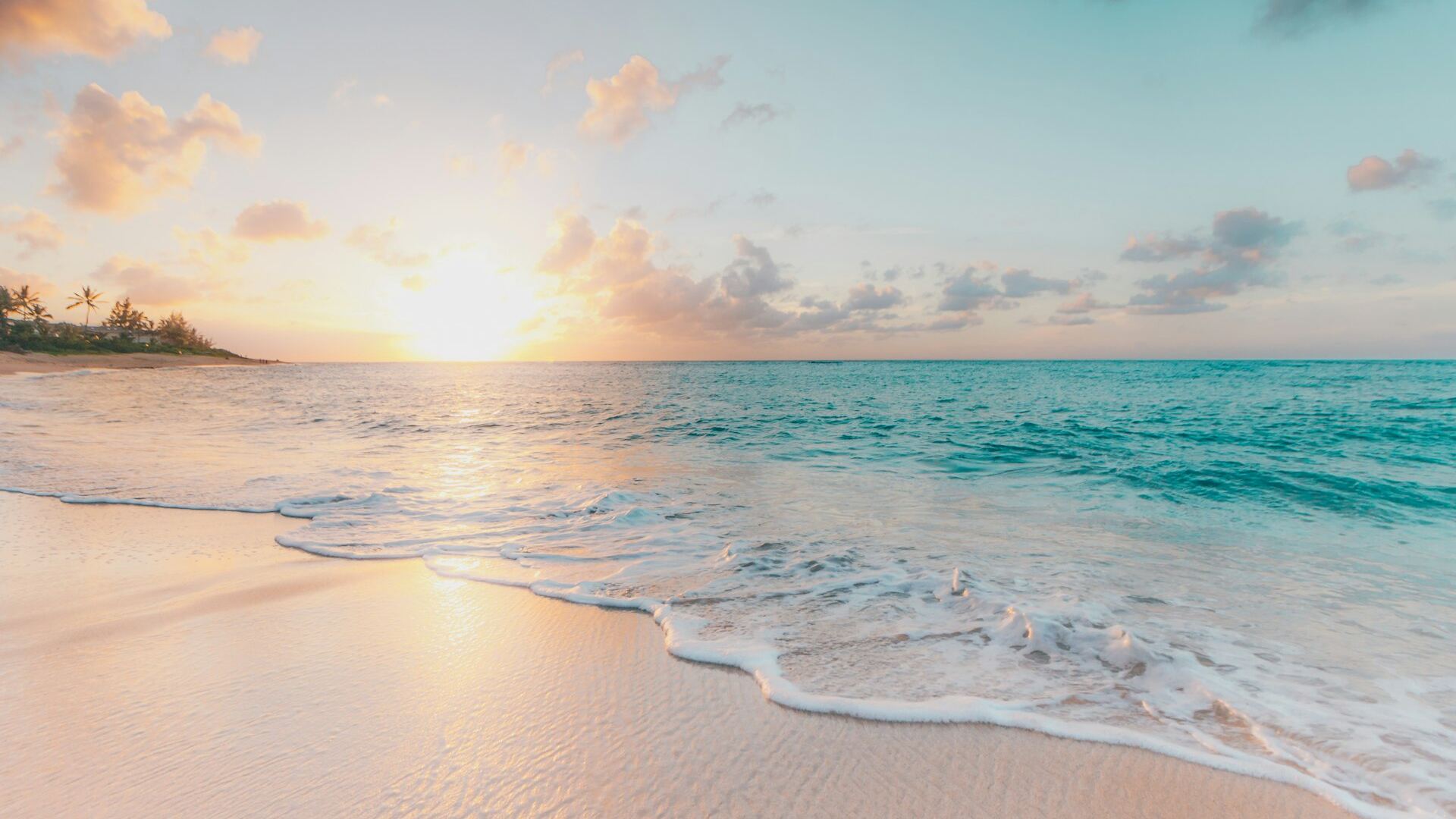 Playa al atardecer con aguas turquesas y reflejo del sol sobre la arena